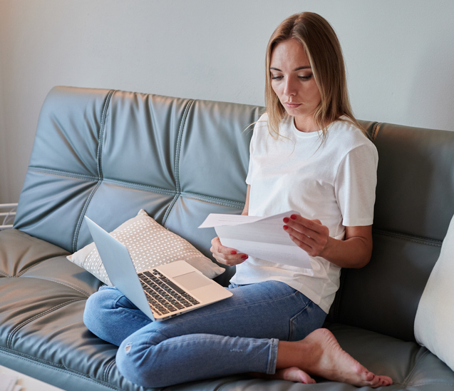 Young female with laptop on the couch reading eviction letter