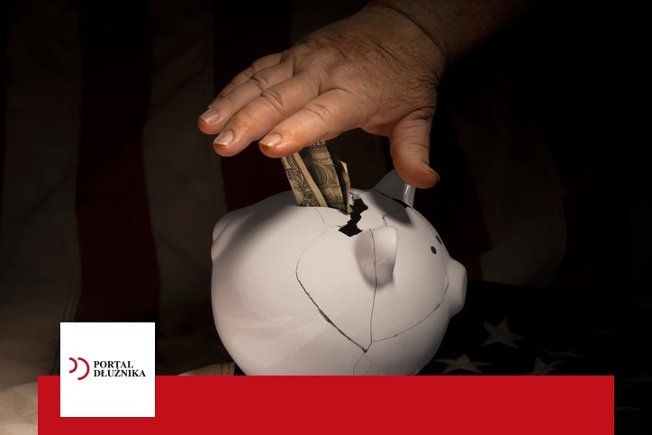 Close-up of older, blue-collar male hands pressing a white piggy bank on the American flag with coins around it, symbolizing budget squeeze. Trudne kredyty i konsolidacja zadłużenia