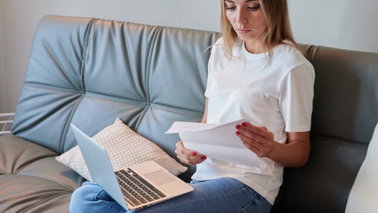 Young female with laptop on the couch reading eviction letter