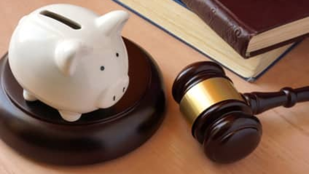 Piggy bank, gavel and books on a table.