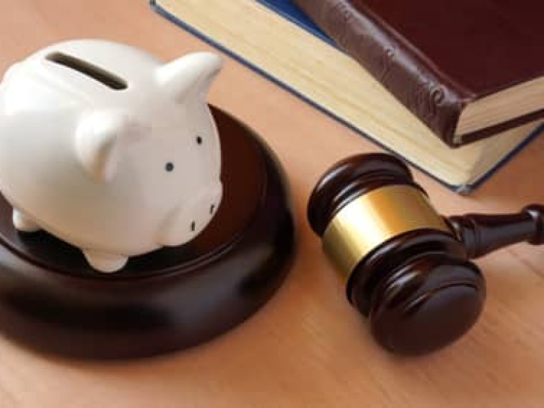 Piggy bank, gavel and books on a table.