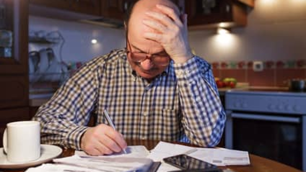 A man tiredly considers the family budget. Lack of money in the crisis.