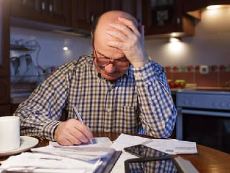 A man tiredly considers the family budget. Lack of money in the crisis.