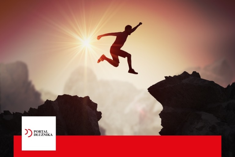 Silhouette of young man jumping over mountains and cliffs at sunset.