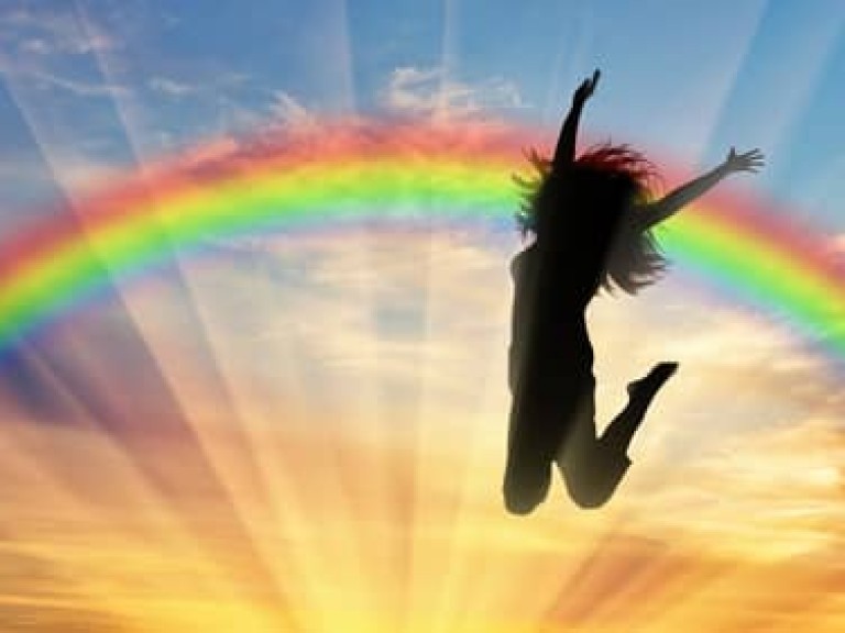 Happy woman jumping near rainbow