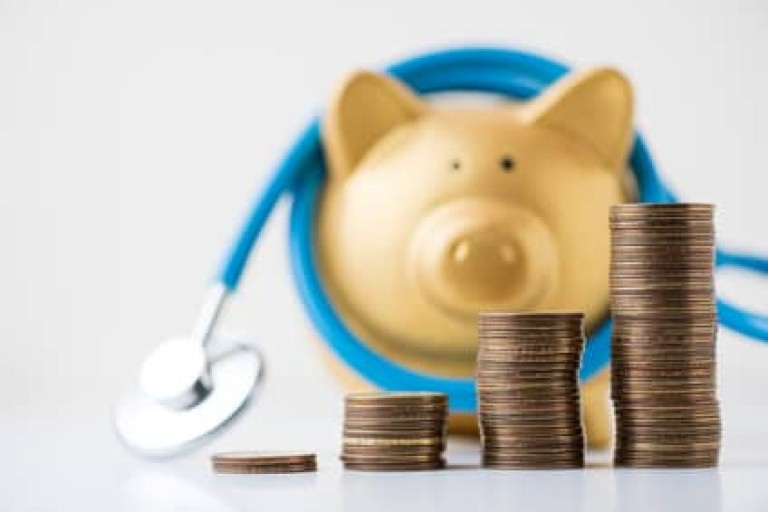 piggy bank with stethoscope and coins stack on white background