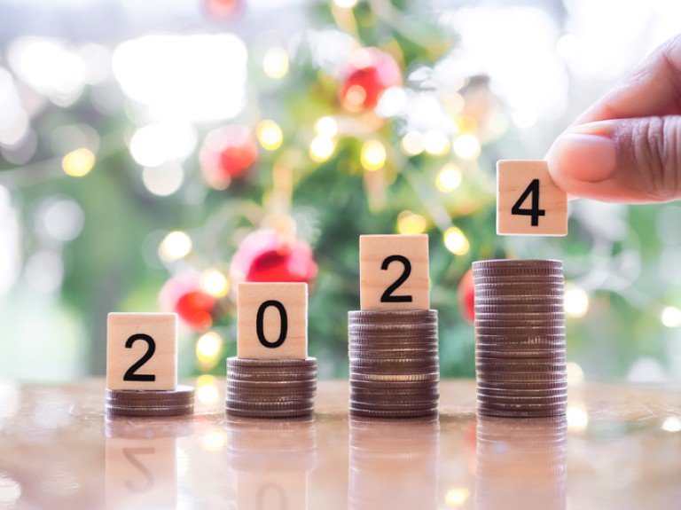 Close up hand putting number 2024 on stack of coins with Christmas light bokeh background. Merry Christmas and Happy New Year, The concept of save money for prepare in new year 2024.