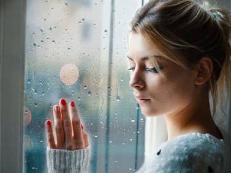 Young girl looking out the window and feeling sad