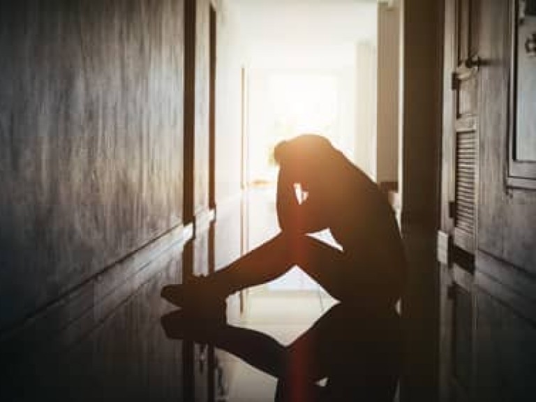 Silhouette of sad and depressed women sitting at walkway of condominium or office with backlit and lens flare,sad mood,feel tired, lonely and unhappy.Vintage style.