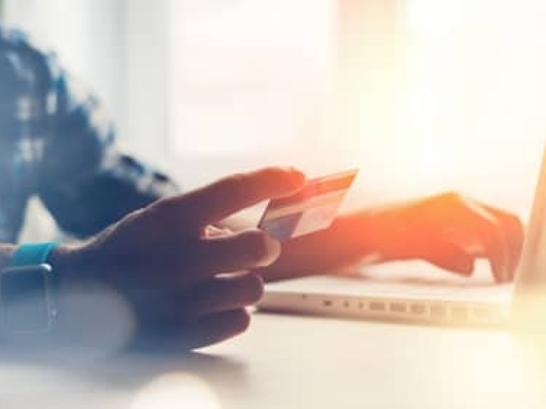 Man holding credit card and using laptop. Online payment (Intentional sun glare and lens flares)