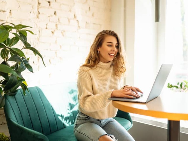 Happy woman sitting on cafe with laptop.