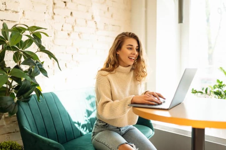 Happy woman sitting on cafe with laptop.