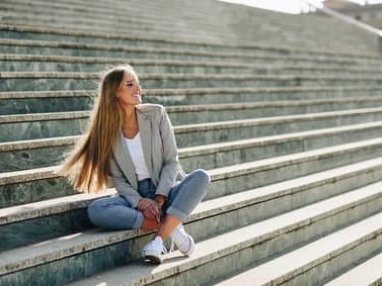 Beautiful young blonde woman smiling on urban steps.