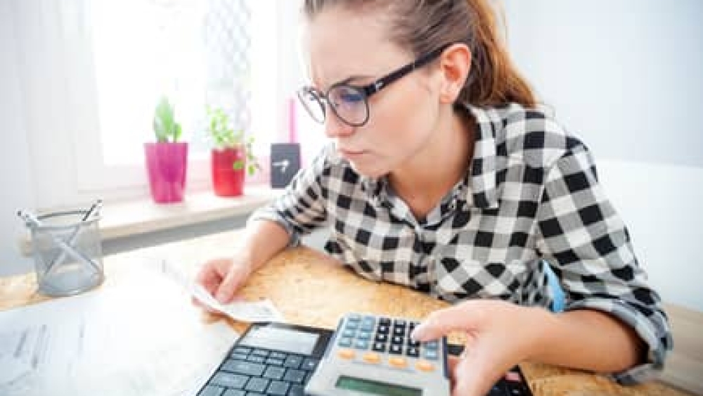 Woman calculating and paying bills in home office