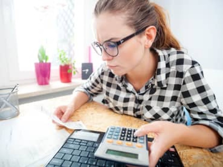 Woman calculating and paying bills in home office