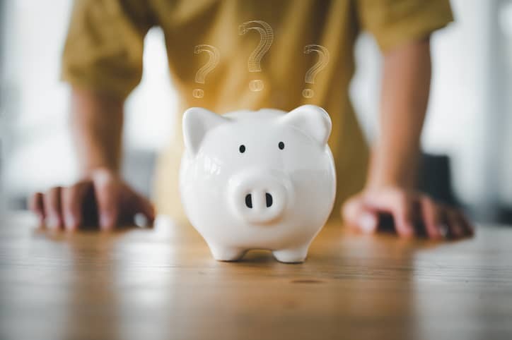 Man stand at desk manage expenses, calculate expenditures, pay bills, makes household finances analysis, closeup on pink piggy bank with Question Mark . Save money for future, be provident concept.