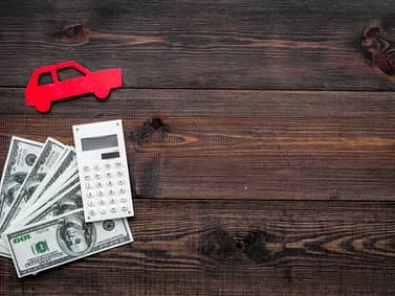 Car credit concept. Money and calculator near car silhouette on dark wooden background top view copy space