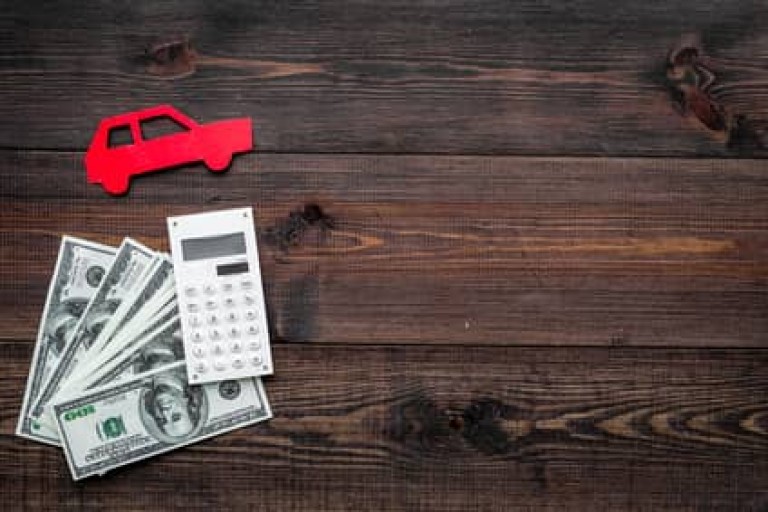 Car credit concept. Money and calculator near car silhouette on dark wooden background top view copy space