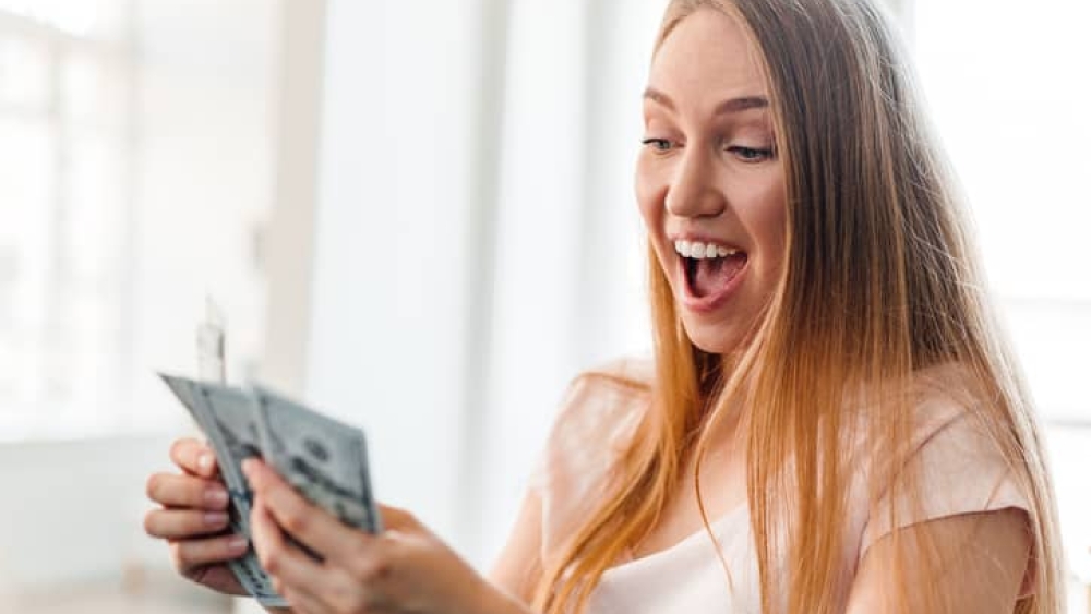 Blonde long-haired woman counting money at home