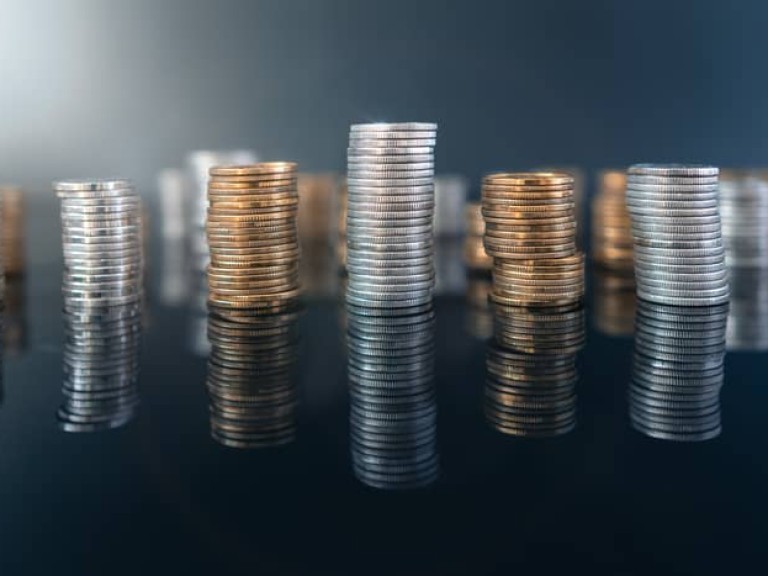 Piles of coins (polish zloty, grosze, PLN) on a black, reflective surface. Inflation consuming our savings. Difficult economy situation in Poland.