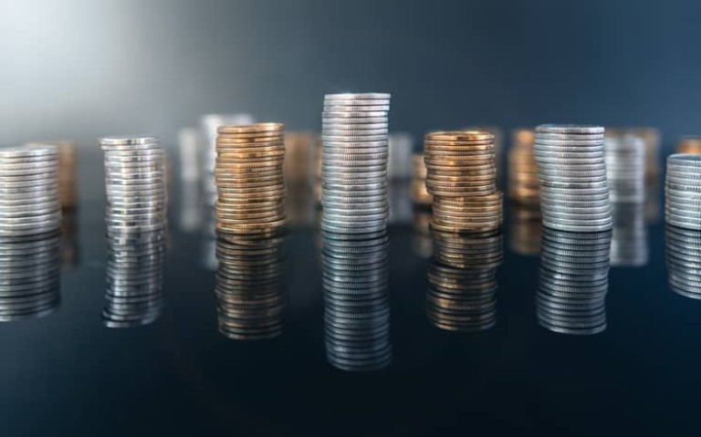 Piles of coins (polish zloty, grosze, PLN) on a black, reflective surface. Inflation consuming our savings. Difficult economy situation in Poland.