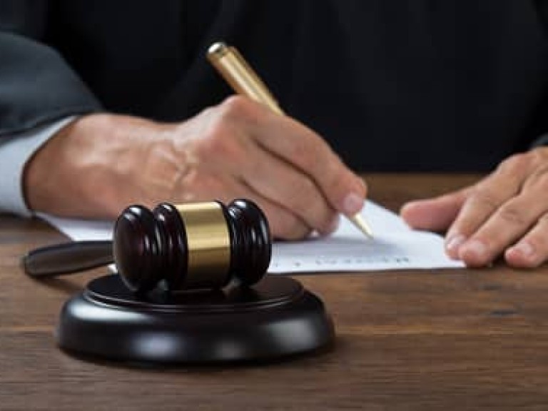 Judge Writing On Paper In Courtroom