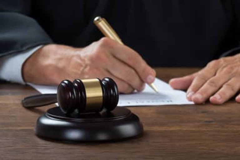 Judge Writing On Paper In Courtroom