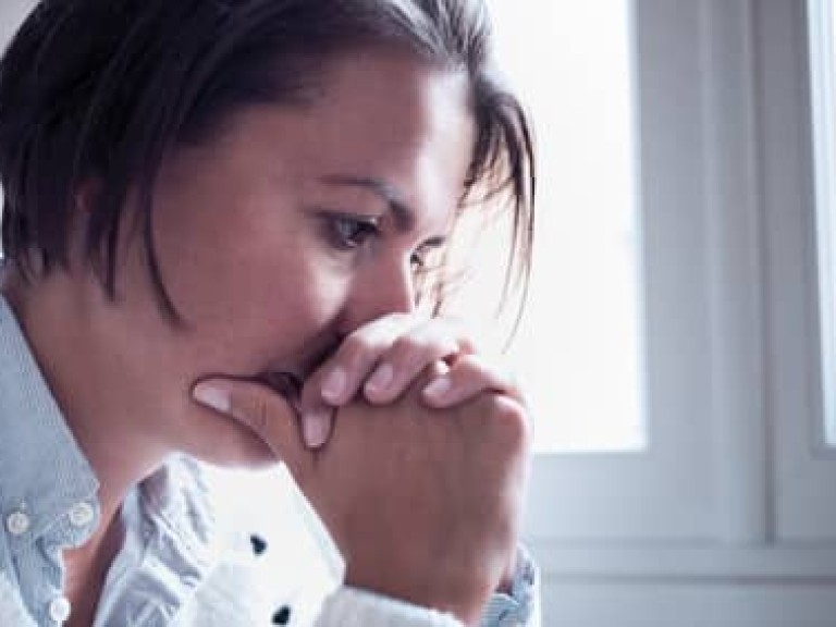 Desperate and sorrowful woman portrait next to window