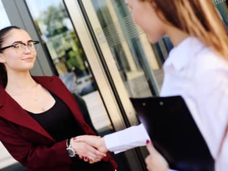 two young cute business women shaking hands.