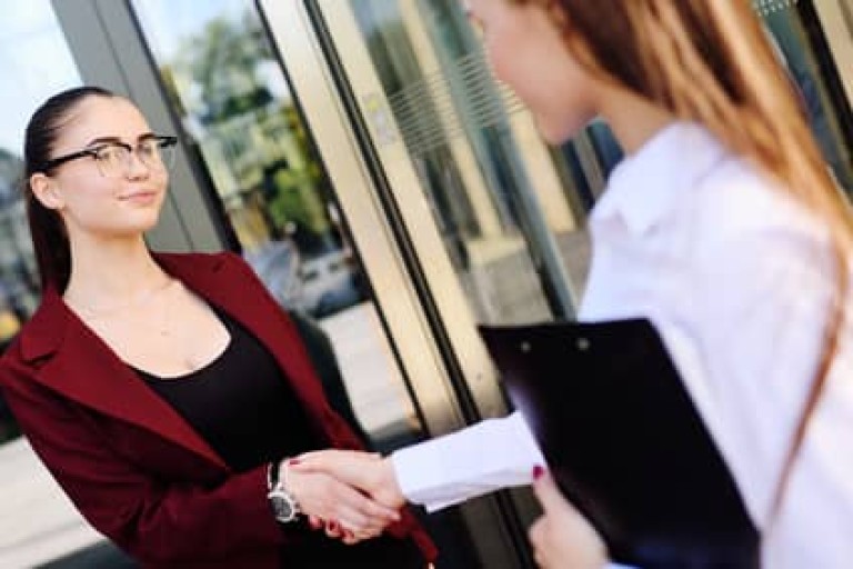 two young cute business women shaking hands.