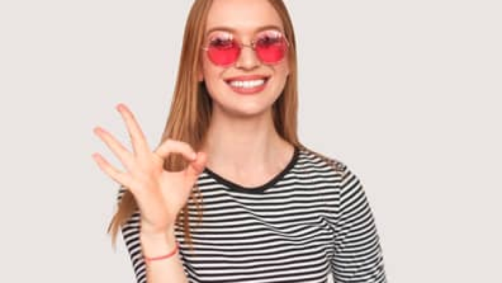Trendy girl showing OK gesture on white